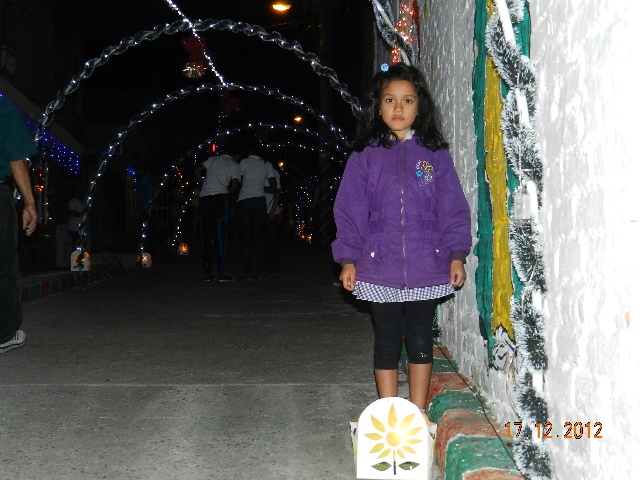 La niña orgullosa posa con los faroles artesanales...